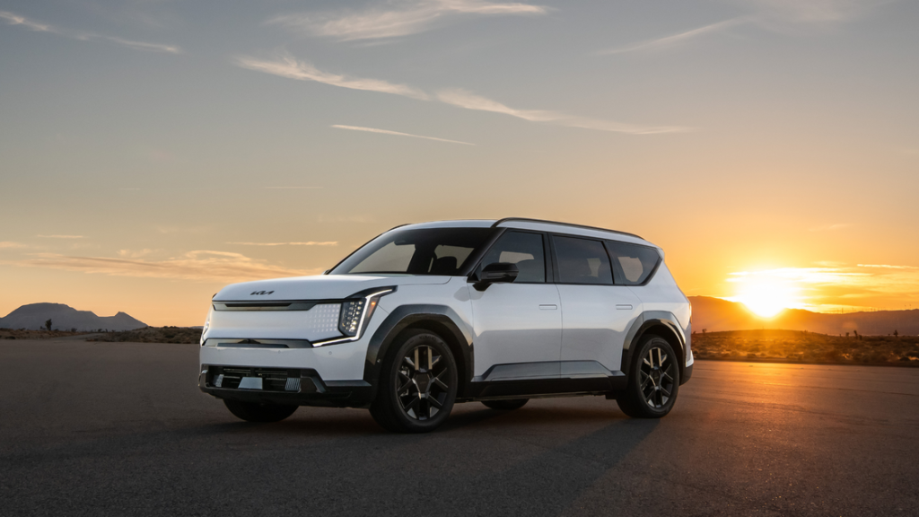2026 Kia EV9 electric SUV in white, parked with sunset backdrop, modern futuristic styling.