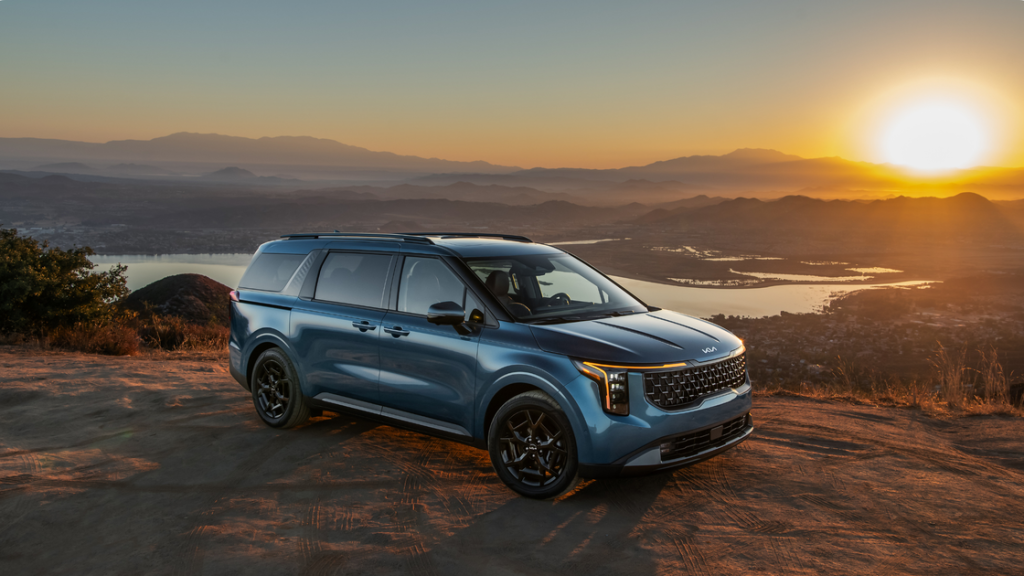 2025 Kia Carnival in blue parked on a mountain overlook at sunset with panoramic scenic views.