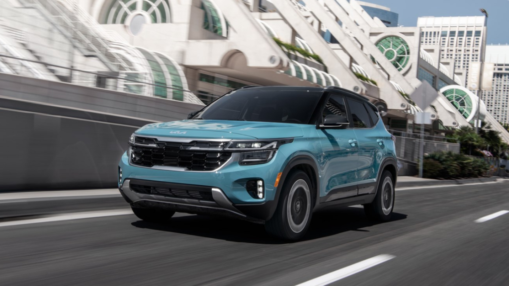 2026 Kia Seltos in teal driving through the city with modern front fascia and aerodynamic design.