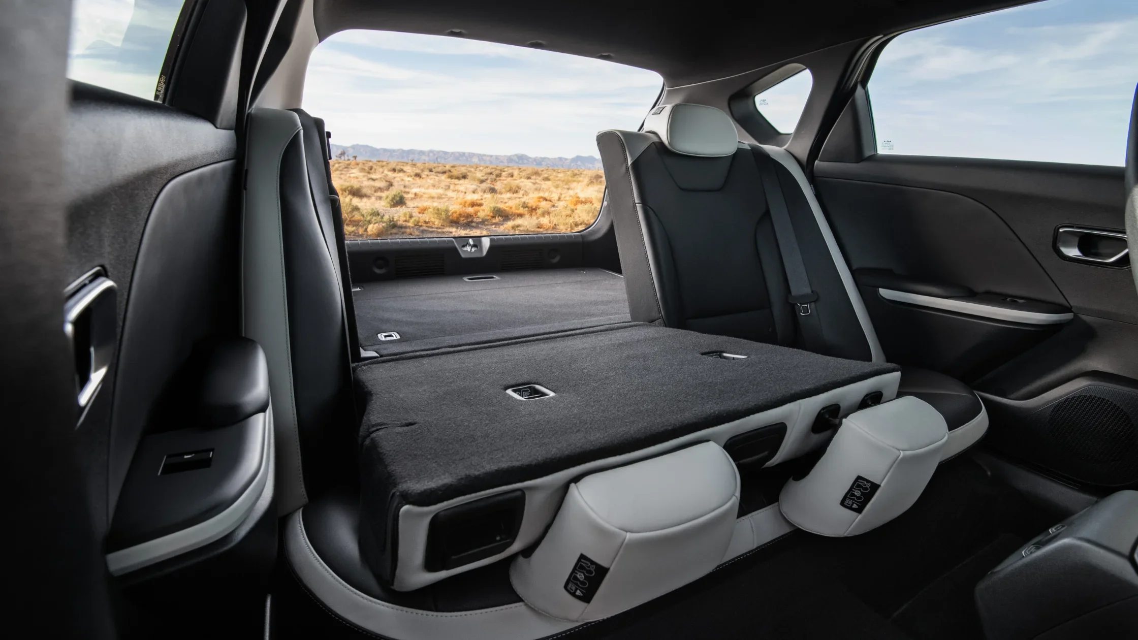 2026 Kia K4 Hatchback rear seats folded flat to expand cargo space in black and white interior.