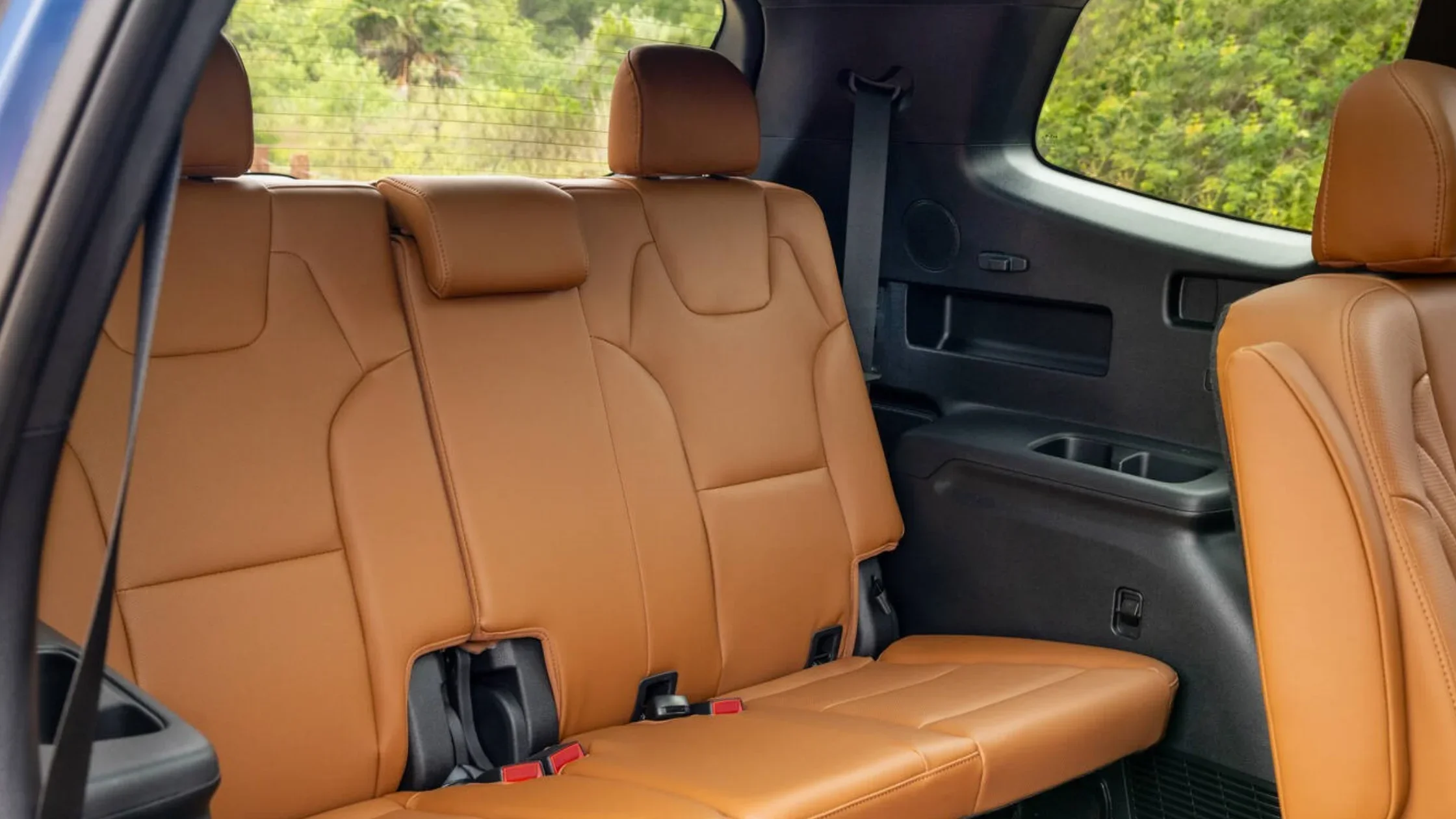 Rear seating area of the 2025 Kia Telluride showcasing brown leather third-row seats and rear side panels with cupholders.