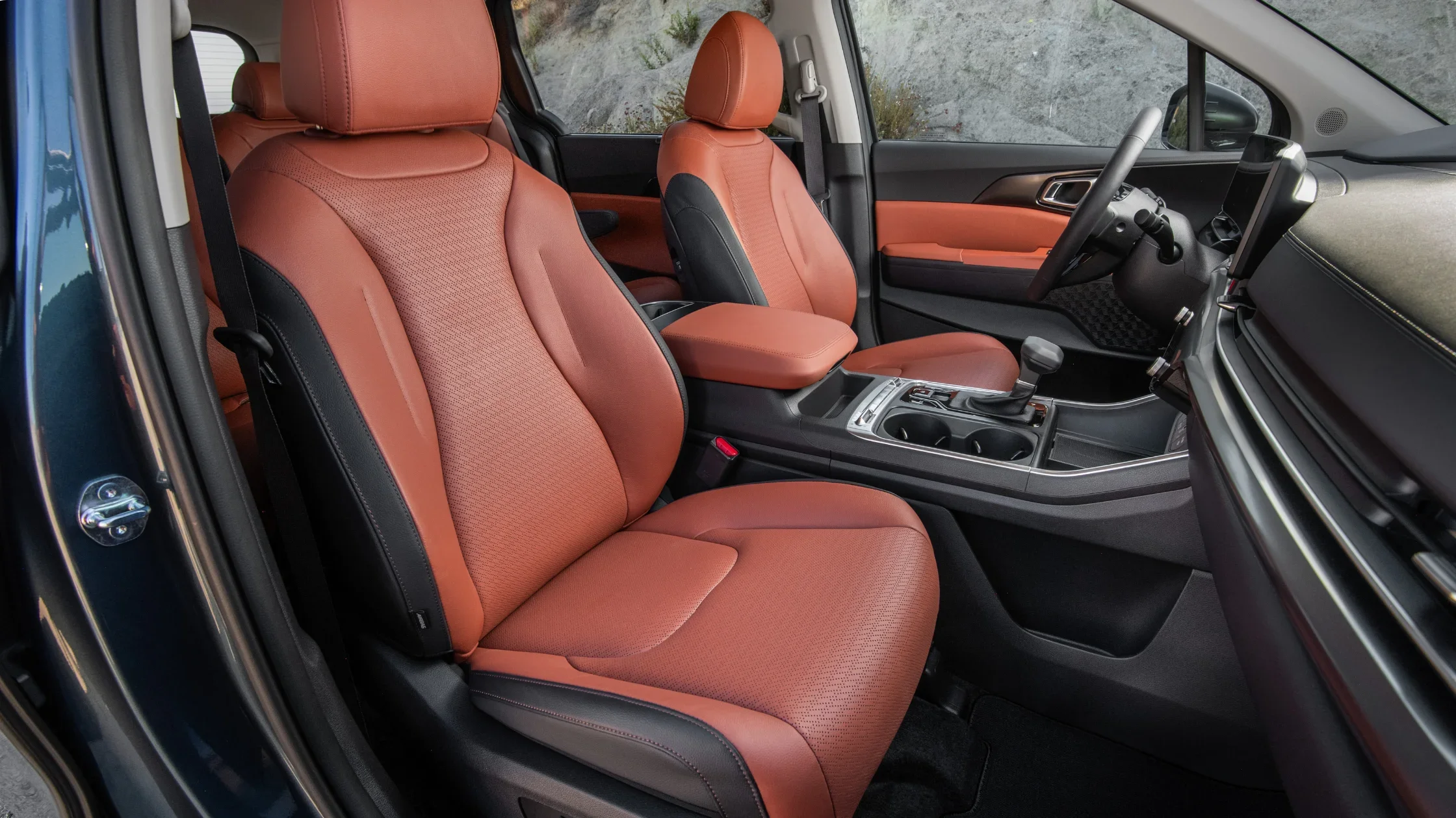 Front cabin of the 2025 Kia Carnival featuring two-tone seats and a modern center console layout.