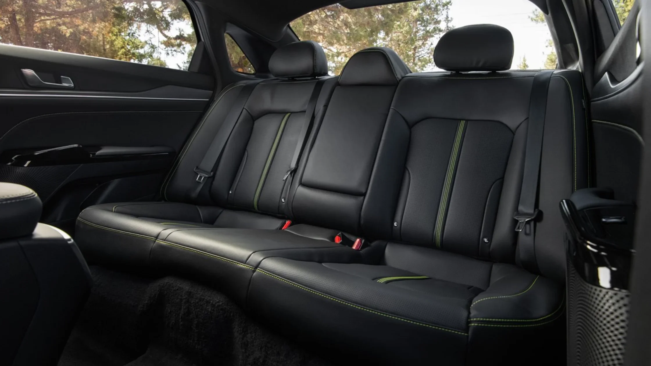 Rear seating of the 2026 Kia K5 displaying black leather upholstery with green contrast stitching.